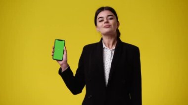 4k video 'da bir kız krom anahtar telefonu kullanıyor ve sarı arkaplanı onaylıyor. Duygu kavramı..