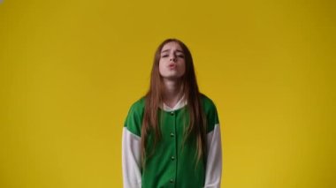 Sarı arka planda bir şey isteyen bir kızın 4K videosu. Duyguların kavramı.