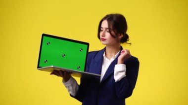 Krom anahtar dizüstü bilgisayar kullanan bir kızın 4K videosu ve sarı arka plan üzerinde düşünme. Duygu kavramı..