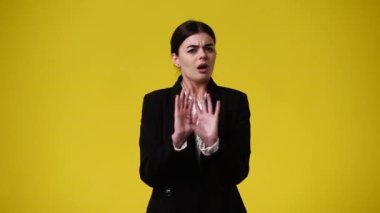 Sarı arka planda dur işareti gösteren bir kızın 4K videosu. Duyguların kavramı.