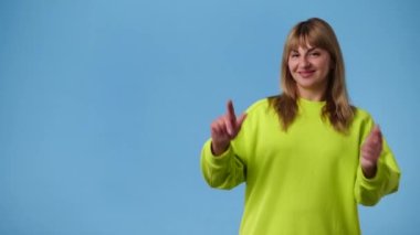 Sol tarafı işaret eden bir kızın mavi arkaplanı gösteren 4K videosu. Duyguların kavramı.