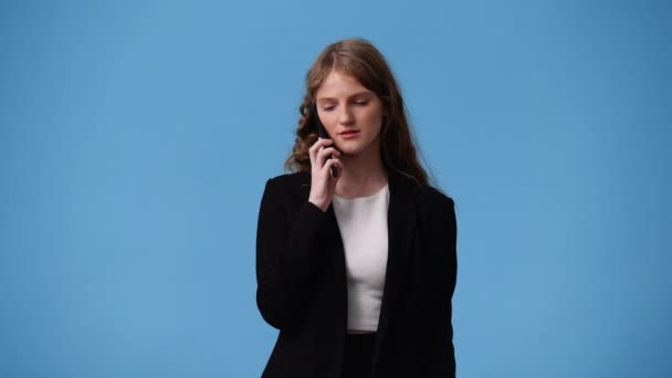 青い背景の上に彼女の携帯電話を使って1人の女の子の4Kビデオ 感情の概念 — ストック動画