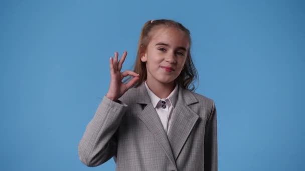 青を背景にOkの看板を見せる可愛い女の子の4K動画 感情の概念 — ストック動画