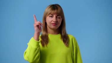 4K video, kızın telefon hareketlerini gösteriyor. Mavi arka planda bana işaret var. İletişim sunan sembol kavramı.