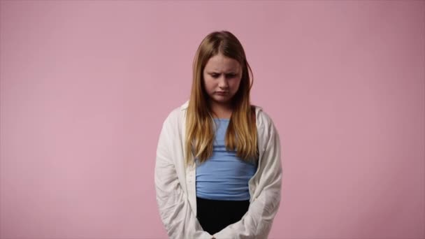 ピンクの背景の上に悲しげに立つ1人の少女の4Kビデオ 感情の概念 — ストック動画
