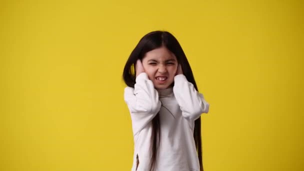 黄色の背景に手で耳を覆う少女の4Kビデオ 感情の概念 — ストック動画