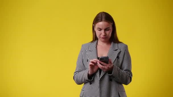 Video Una Donna Indica Destra Tenendo Telefono Mano Sfondo Giallo — Video Stock