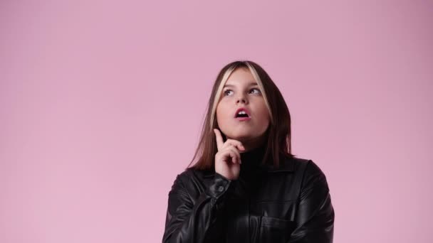 ピンクの背景を指差す1人の少女の4K動画 感情の概念 — ストック動画