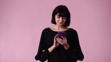 Pembe arka planda mesaj yazan ve gülümseyen bir kadının 4K videosu. Duyguların kavramı.
