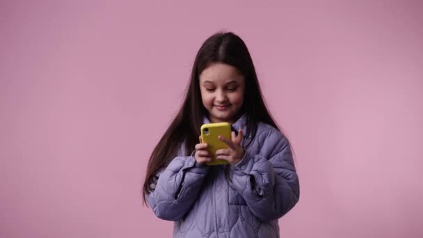 一个孩子在粉色背景下笑着打字的4K视频 情绪的概念 — 图库视频影像