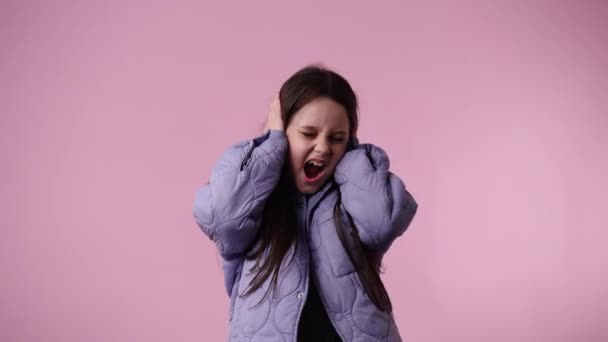 ピンクの背景の上にノイズから耳をカバーする1人の子供の4Kスローモーションビデオ 感情の概念 — ストック動画