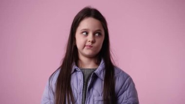 Pembe arka planda sessizlik işareti gösteren bir çocuğun 4K videosu. Duyguların kavramı.