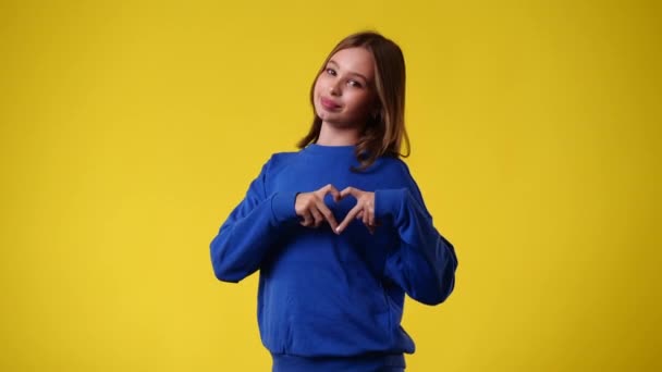 4K慢镜头 一个女孩在黄色背景上用双手表示爱意 情绪的概念 — 图库视频影像