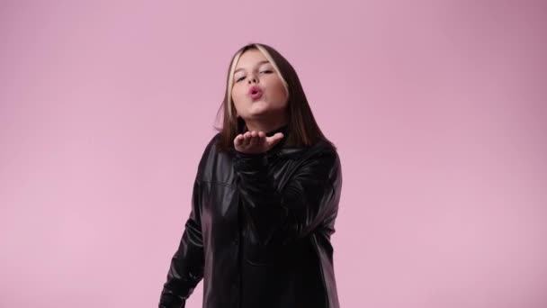 ピンク色の背景に空気のキスを送る1人の少女の4K動画 感情の概念 — ストック動画