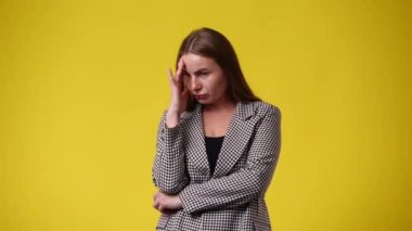 Sarı arka plandaki bir şeyden endişelenen bir kadının 4K videosu. Duyguların kavramı.