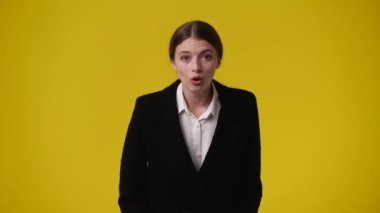 Sarı arka plana şaşırmış bir kızın 4K videosu. Duyguların kavramı.