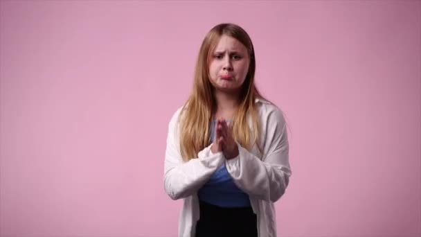 ピンクの背景で嘆願する1人の少女の4K動画 感情の概念 — ストック動画