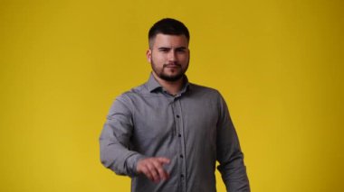 Sarı arka planda negatif yüz ifadesi olan bir adamın 4K videosu. Olumsuz duygu kavramı.