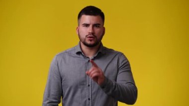 Sarı arka plandaki bir video için poz veren bir adamın 4K videosu. Duyguların kavramı.