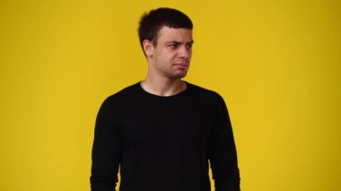 Sarı arka plandaki bir video için poz veren bir adamın 4K videosu. Duyguların kavramı.