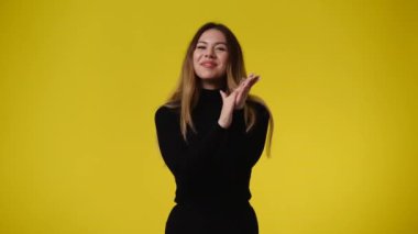 Sarı arka planda poz veren bir kızın 4K videosu. Duyguların kavramı.