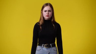 Sarı arka planda düşünceli yüz ifadesi olan bir kızın 4K videosu. Fikirleri olan kız kavramı.