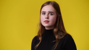 Sarı arkaplan üzerinde bir video için poz veren bir kızın 4K videosu. Fikirleri olan kız kavramı..