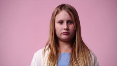Pembe arka planda ne yazık ki poz veren bir kızın 4K yavaş çekim videosu. Duyguların kavramı.