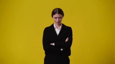 4k video of one girl who crosses her arms and responds negatively to something over yellow background. Concept of emotions.