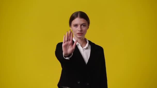 黄色の背景の上に何かに立ち止まり否定的に反応する1人の少女の4Kビデオ 感情の概念 — ストック動画