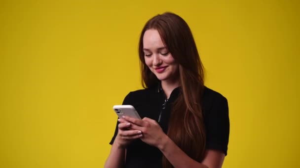 Vídeo Uma Garota Que Sorri Digita Texto Sobre Fundo Amarelo — Vídeo de Stock