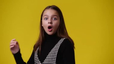 Sarı arka planda şok olmuş yüz ifadesi olan bir kızın 4K videosu. Şok olmuş yüz ifadesi olan kız kavramı .