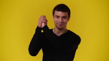 Sarı arka planda kameraya bakan bir adamın 4K videosu. Duyguların kavramı.