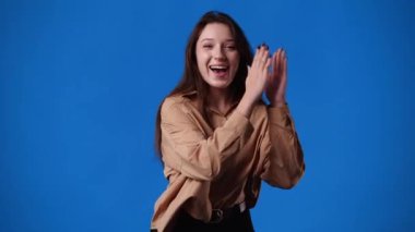 4k video of one girl pointing at right and showing thumb up over blue background. Concept of emotions.