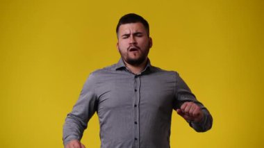 Sarı arka plandaki bir video için poz veren bir adamın 4K videosu. Duyguların kavramı.