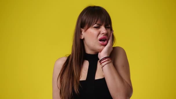 黄色い背景に歯痛のある1人の女の子の4Kビデオ 感情の概念 — ストック動画