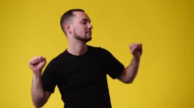 Sarı arka planda dans eden bir adamın 4K videosu. Duyguların kavramı.