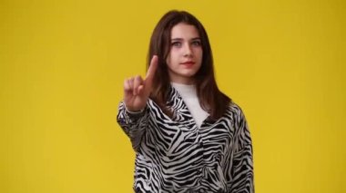 Sarı arka plandaki bir şeye negatif tepki veren bir kızın 4k yavaş çekim videosu. Duyguların kavramı.