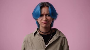 4k slow motion video of one girl who responds negatively to something over pink background. Concept of emotions.