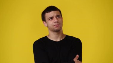 Sarı arka planda bir şey düşünen bir adamın 4K videosu. Duyguların kavramı.