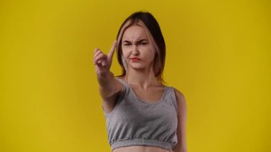 Sarı arka plandaki bir şeye negatif tepki veren bir kızın 4K videosu. Duyguların kavramı.