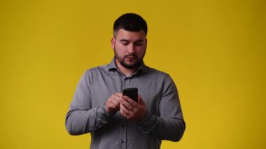 Telefonda konuştuktan sonra sarı arka planda duygusal olarak sevinen bir adamın 4K videosu. Duyguların kavramı.