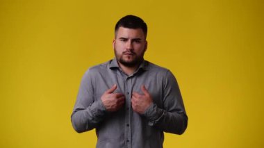 Sarı arka plandaki bir şeye negatif tepki veren bir adamın 4K videosu. Duyguların kavramı.