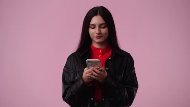 Video Van Een Meisje Typen Tekst Telefoon Glimlachen Roze Achtergrond — Stockvideo