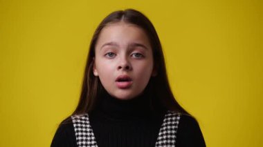 Sarı arka planda ne yazık ki poz veren bir kızın 4K yakın çekim videosu. Duyguların kavramı.