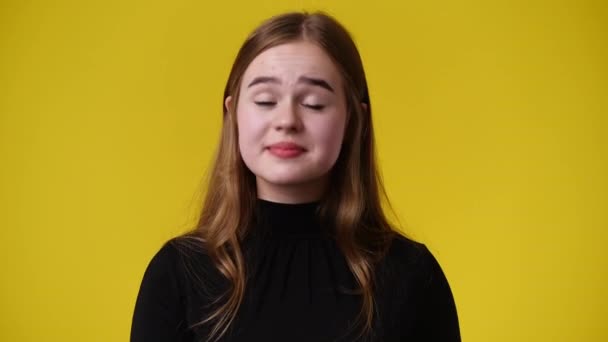 黄色の背景の上に何かに同意する1人の女の子の4Kスローモーションビデオ 感情の概念 — ストック動画