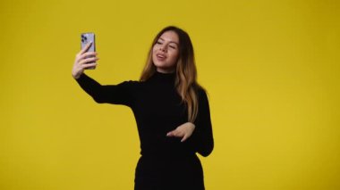 4k video of one girl who talking to someone on a video call over yellow background. Concept of emotions.