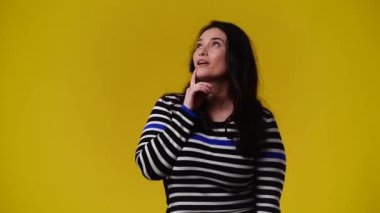 Bir şey arayan ve sarı arkaplanı işaret eden bir kadının 4K videosu. Duyguların kavramı.