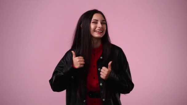 4K段女孩竖起大拇指 在粉色背景下微笑的视频 情绪的概念 — 图库视频影像