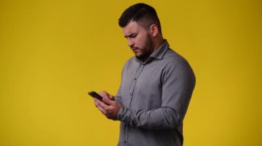 Sarı arka planda telefonu kullanan bir adamın 4K videosu. Duyguların kavramı.